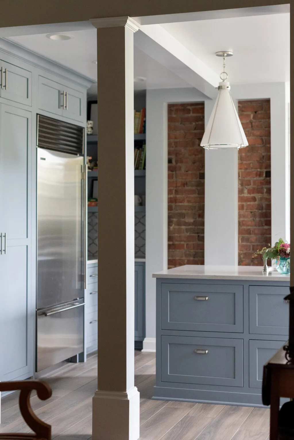 luxury kitchen appliances and painted cabinetry with exposed brick design and modern pendant light
