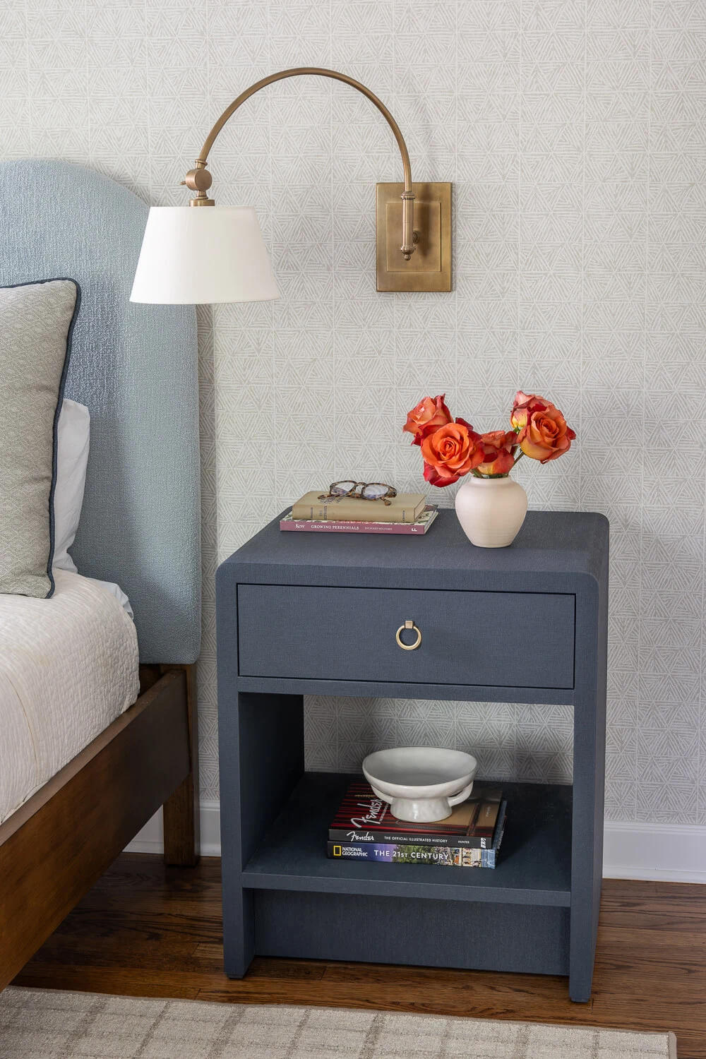 Nightstand in primary bedroom with golden light sconce