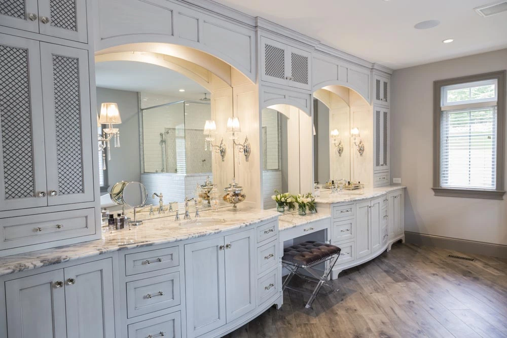 Custom white built in cabinetry along wall with his and hers sinks and vanity in the center