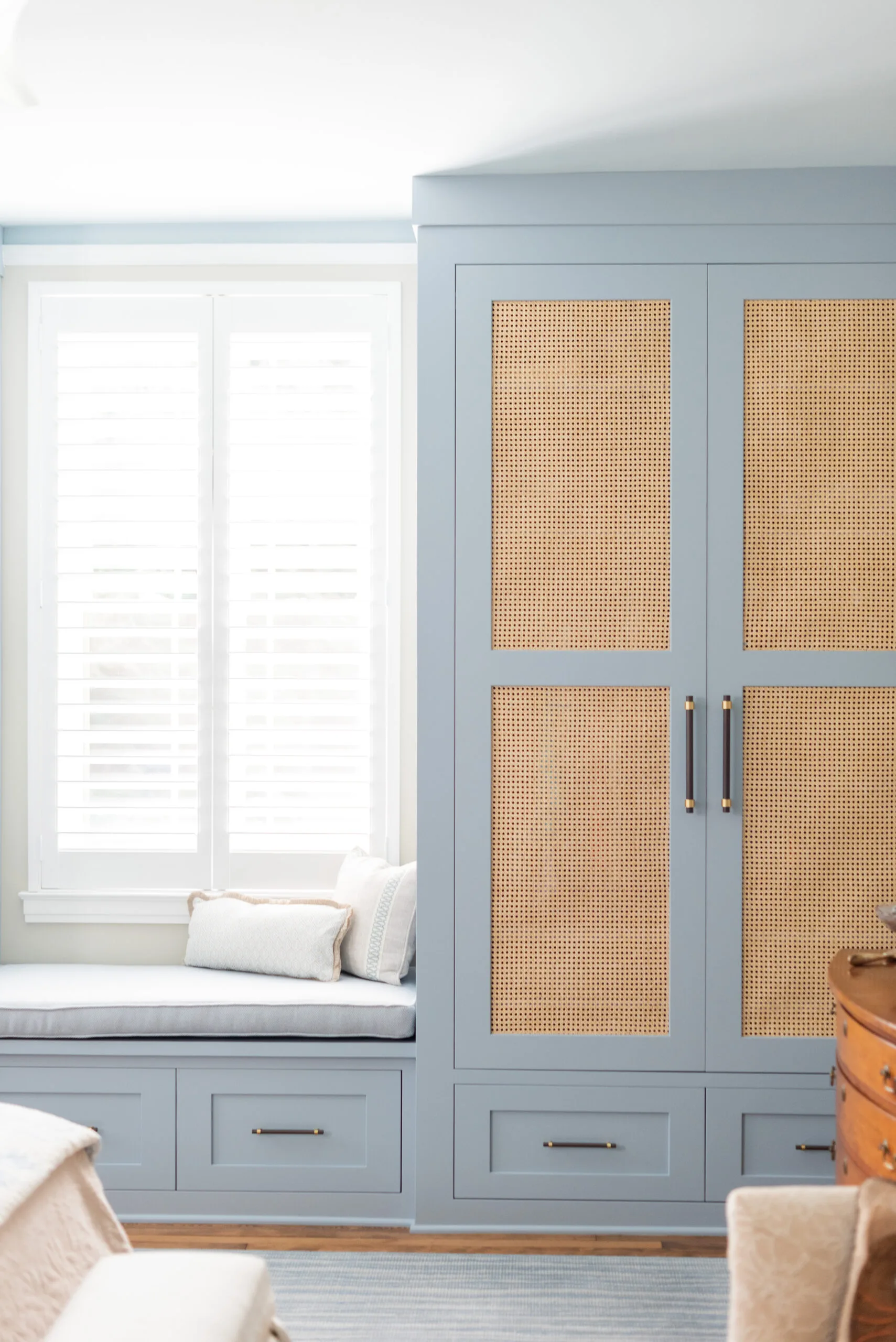 primary bedroom custom closet built ins painted in blue with rattan door insert