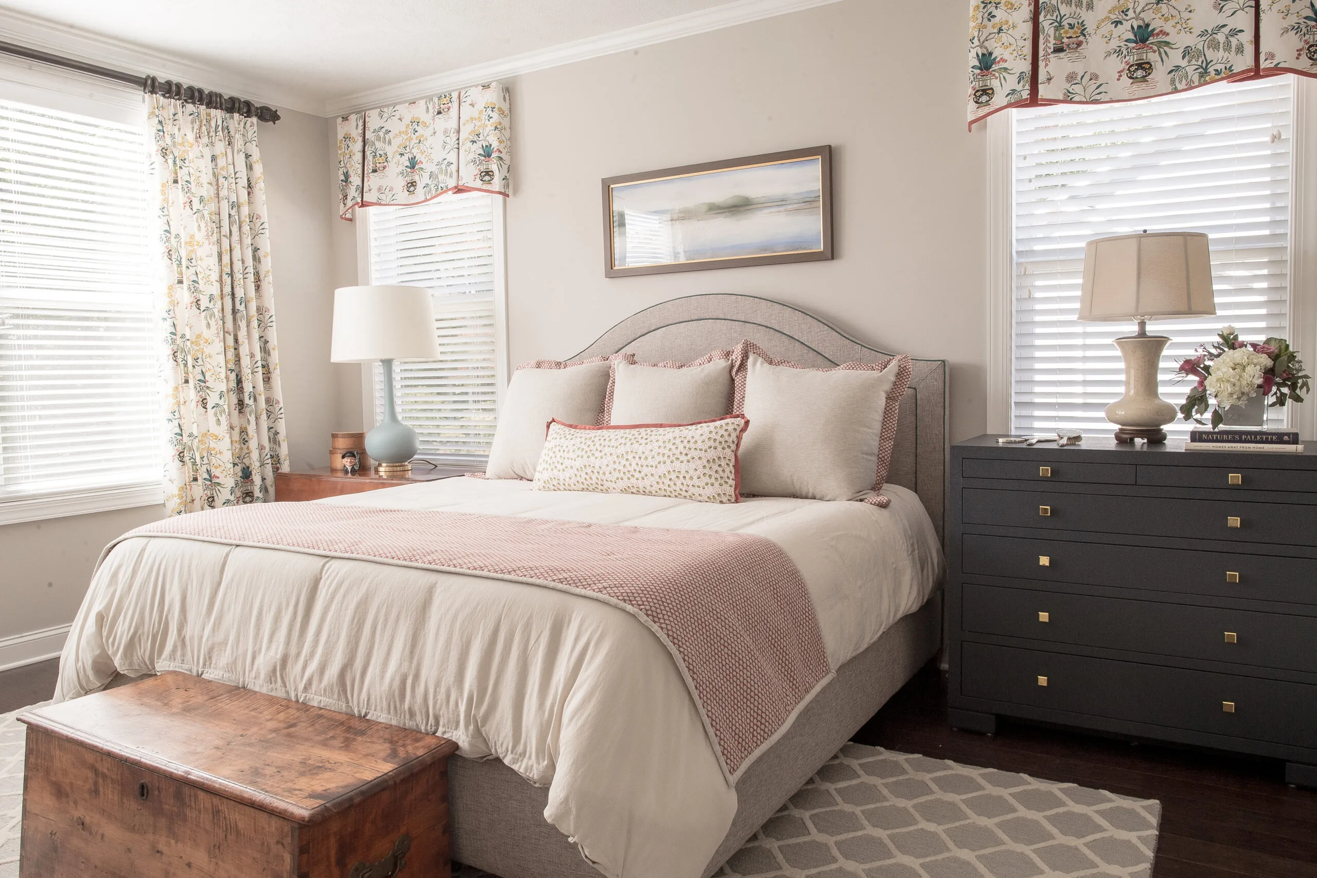 cozy, inviting master bedroom with white linens and artwork above the bed