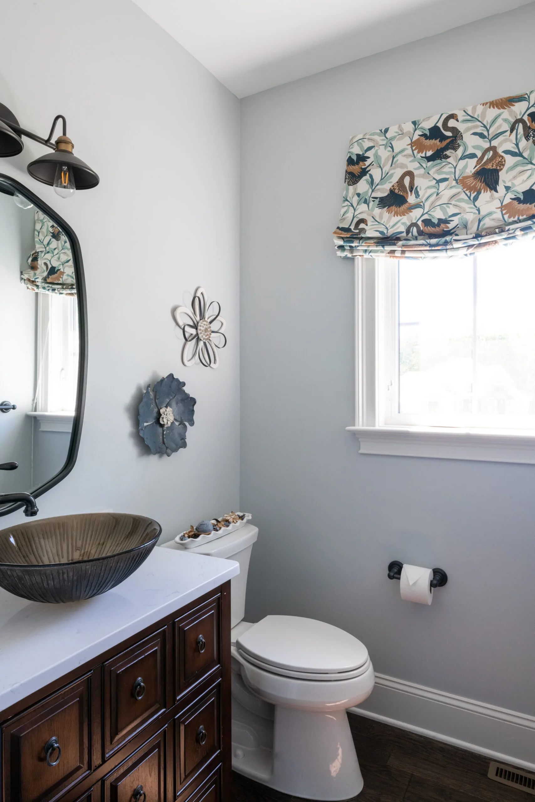 Powder room with dark wood tones and light neutral colors, with a vessel sink and colorful relaxed roman shade