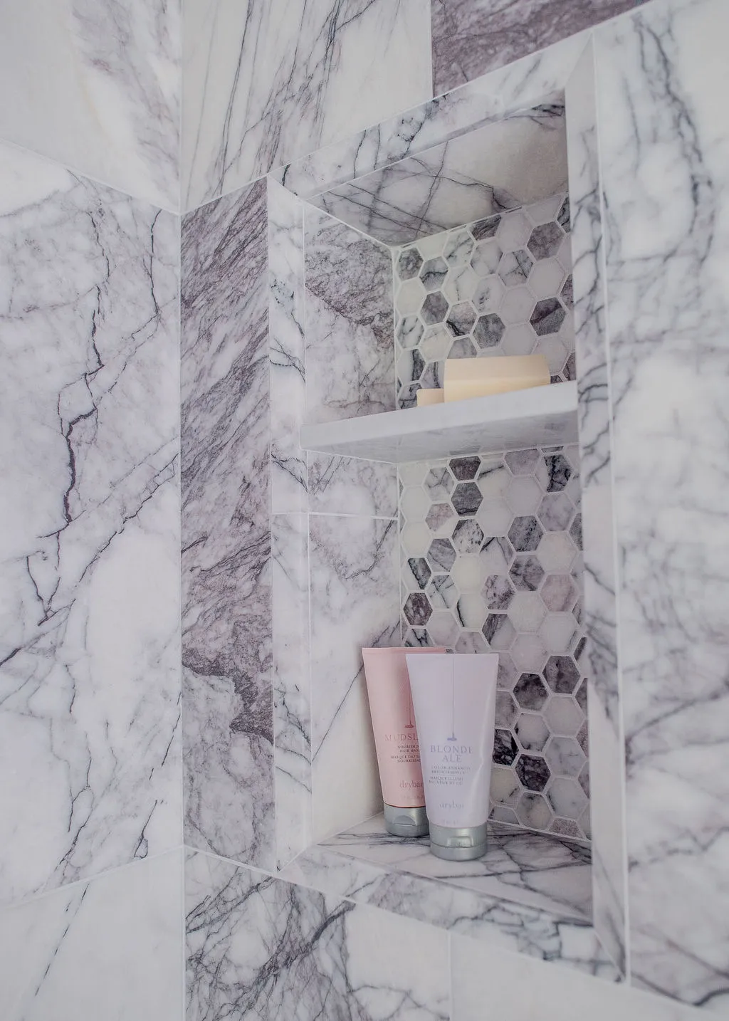 Purple tile inset in shower with shampoo and soap