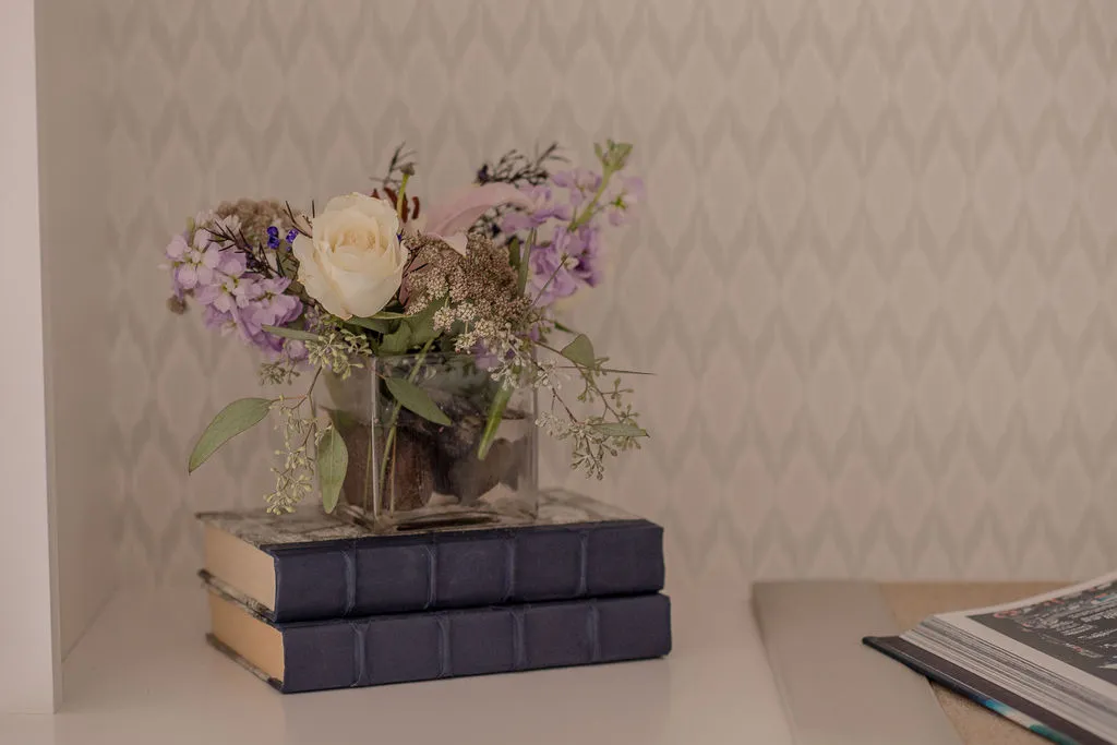 Books used as a stand for a small floral arrangement