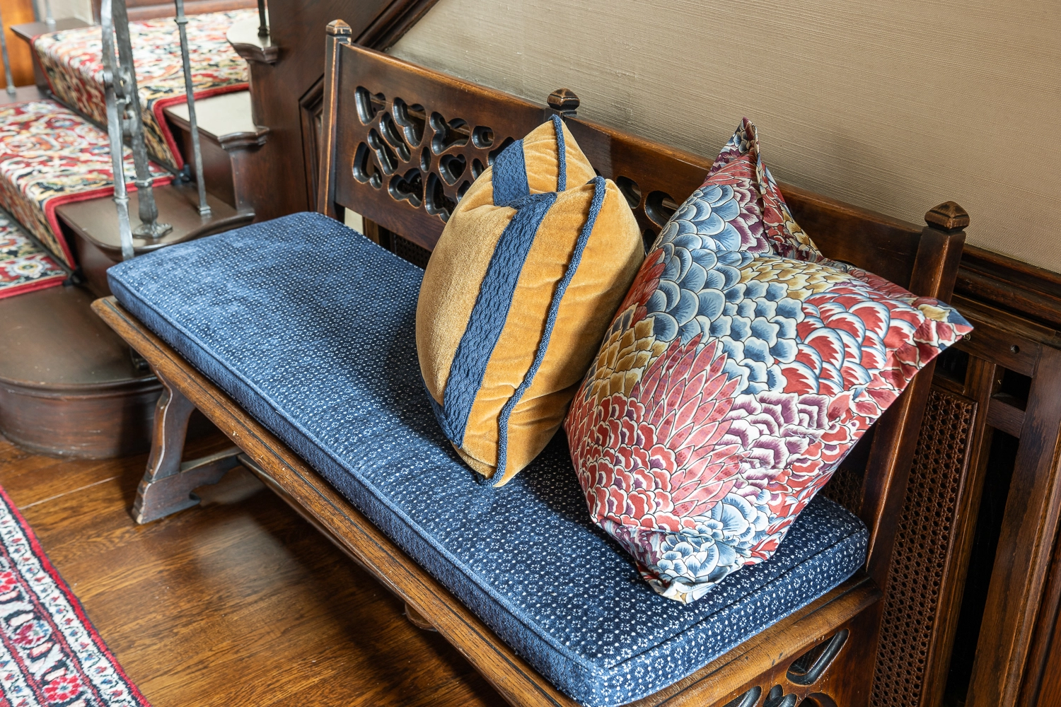 Image of a wooden upholstered bench with two decorative pillows