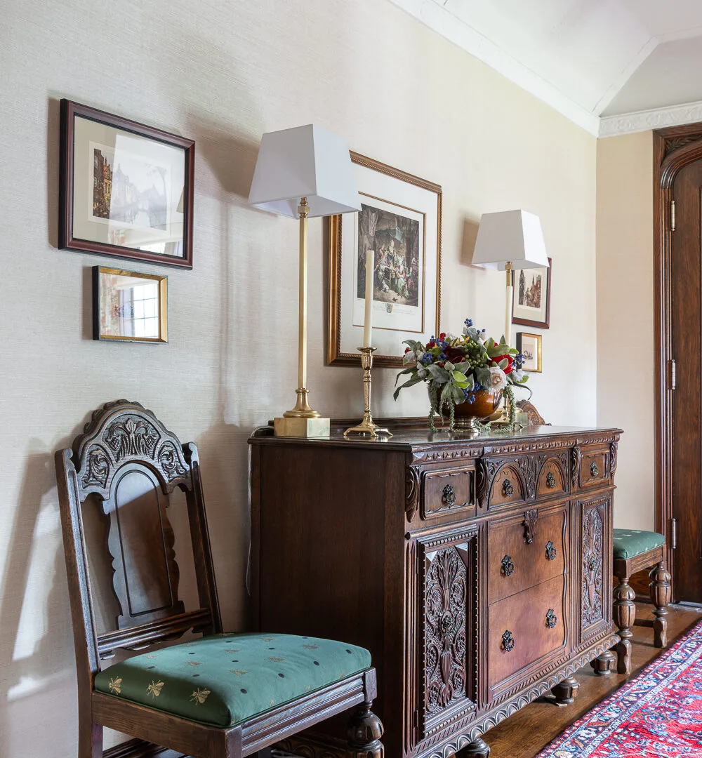 Image of a hallway with a wooden chest beside a chair and artwork above