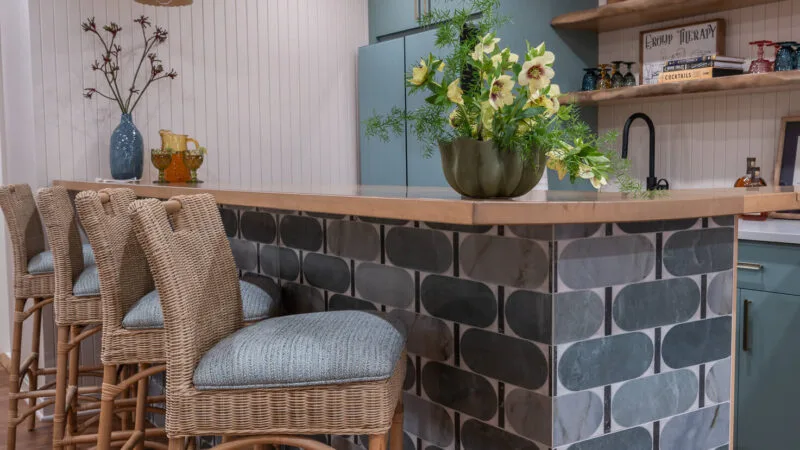 basement bar with blue patterned tiles and woven bar stools