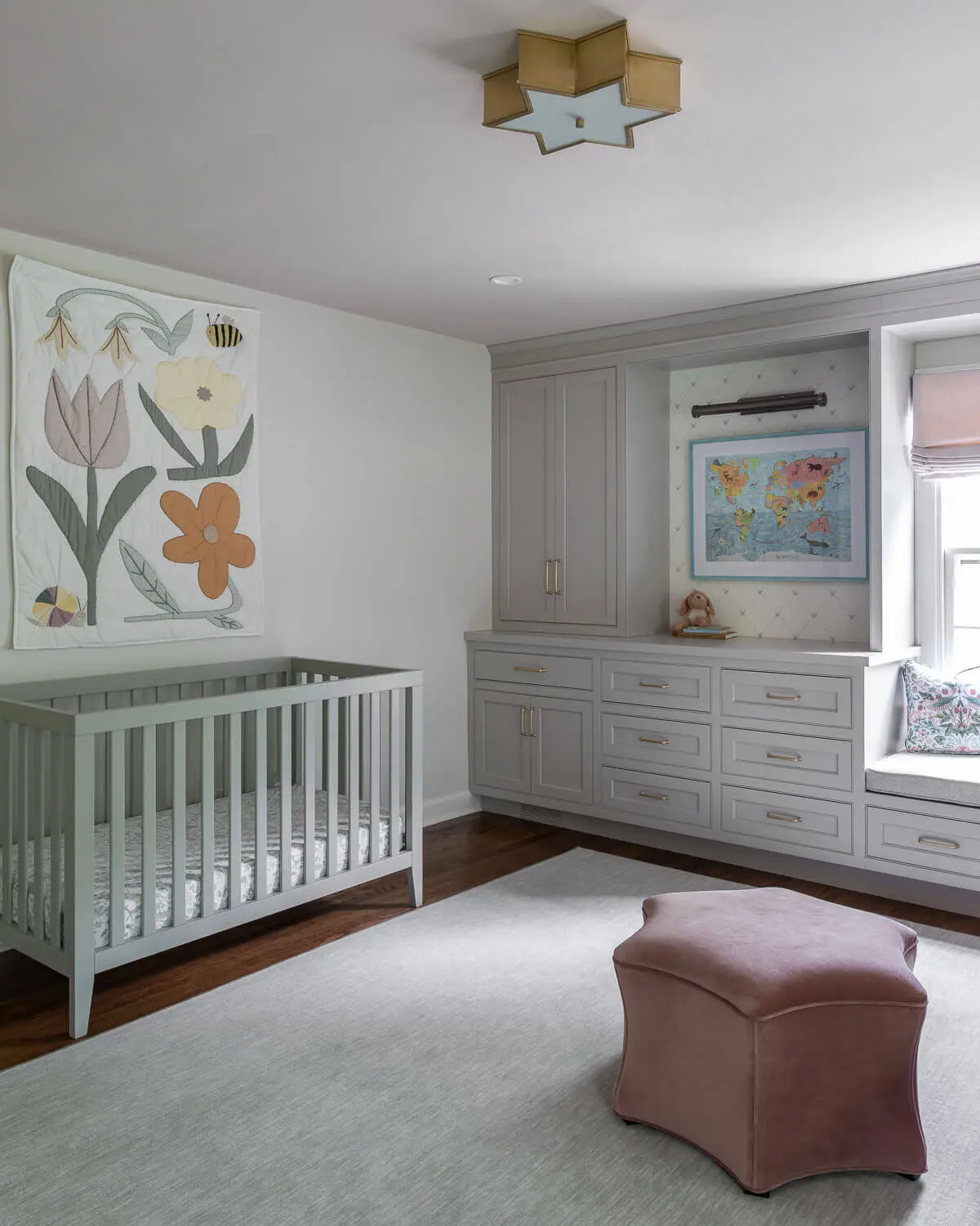 nursery with custom cabinetry, colorful artwork and brass light fixtures