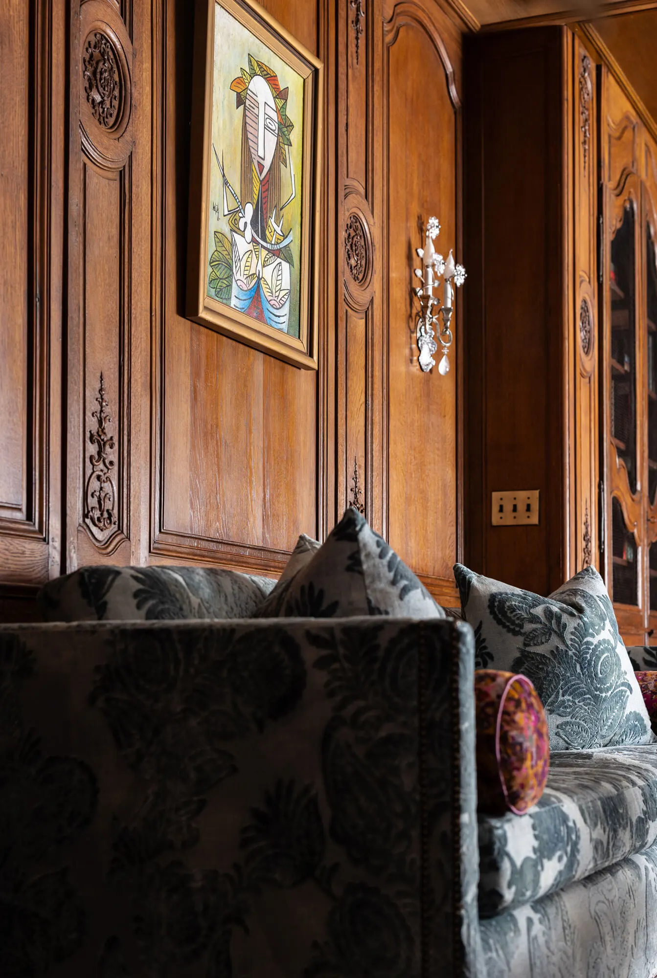 Ornate details, artwork, and sconces all bring out the rich character of the wall's floor-to-ceiling paneling
