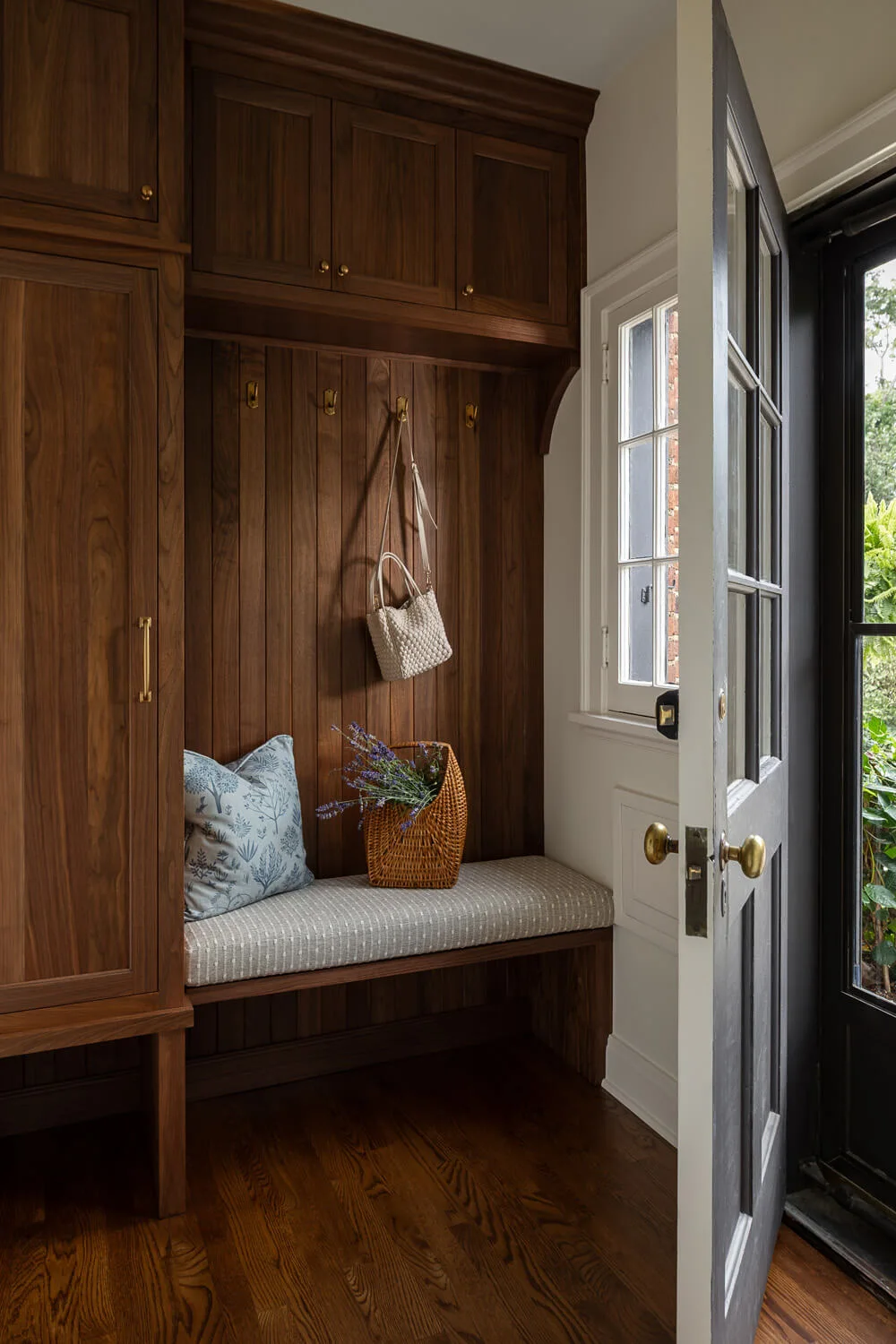 built-in seating and cabinetry inside mudroom with dark wood tones